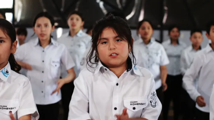 Alumna con la camisa del uniforme Komensky canta con el coro